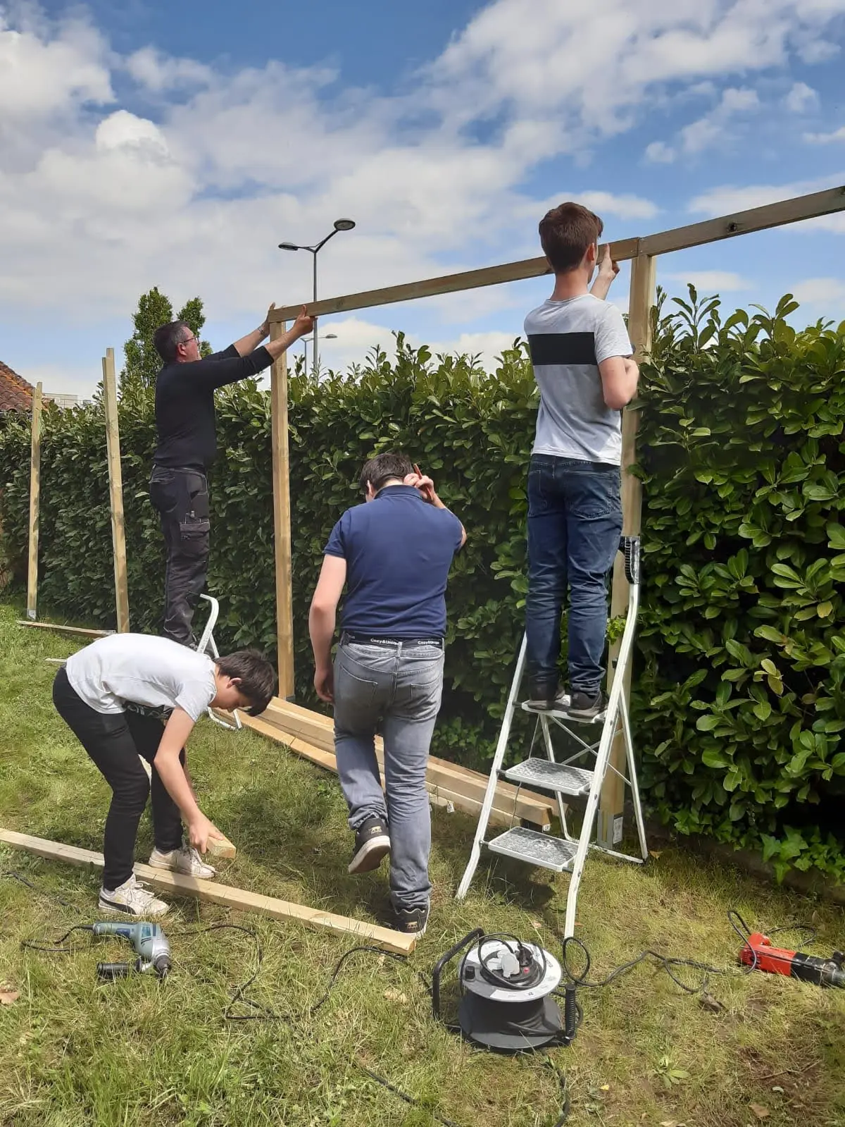 Groupe de bénévoles construisant une palissade en bois lors d'un chantier participatif à Castillon-la-Bataille