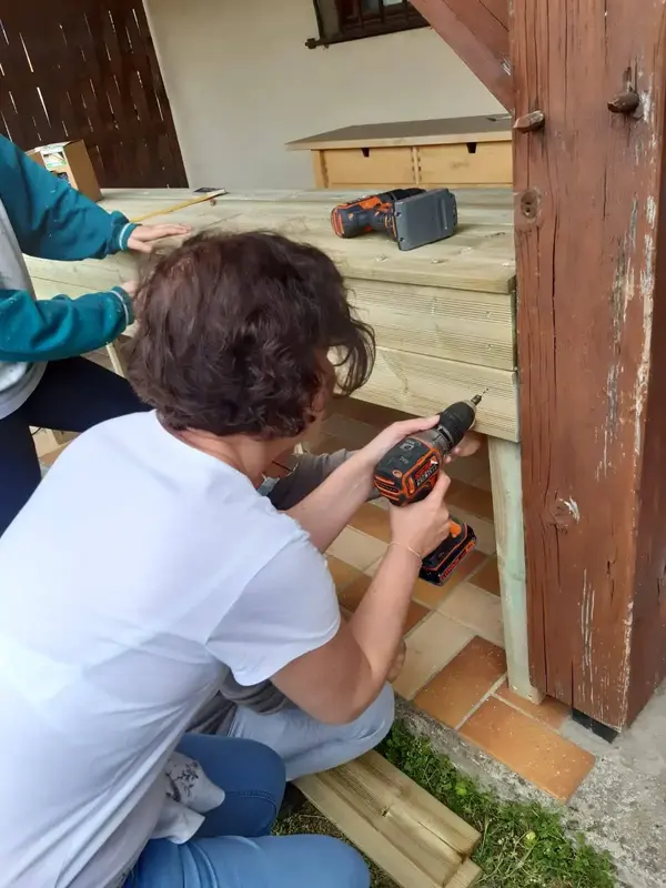 Participant vissant une structure en bois à la perceuse